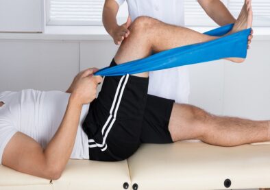 Physiotherapist Helping Patient While Stretching His Leg